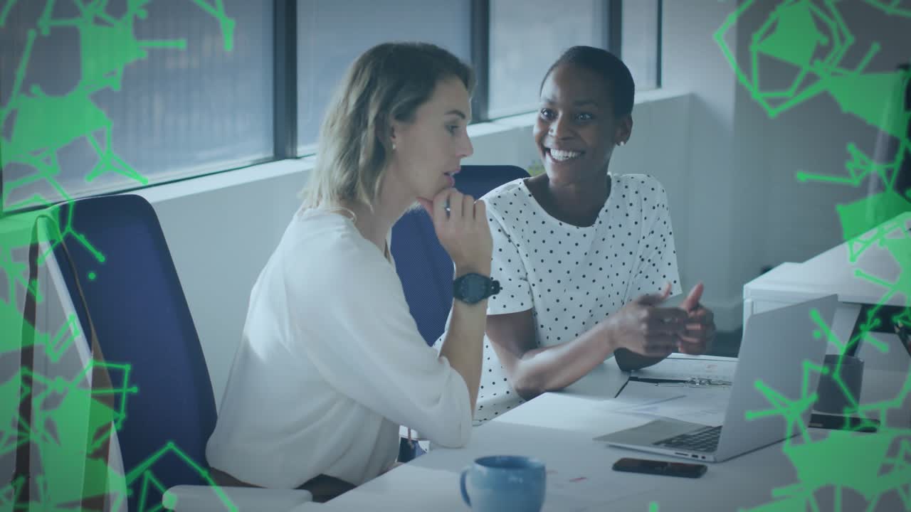 Left woman speaking and gesturing, causing green net, peer typing and editing tech data on laptop