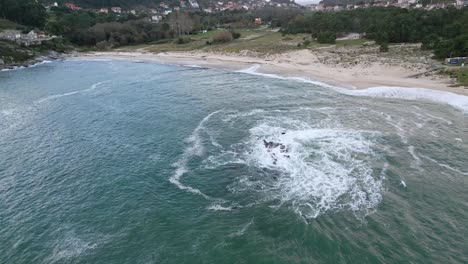 Empty-white-sand-beach-and-rocks-surrounded-by-green-grass