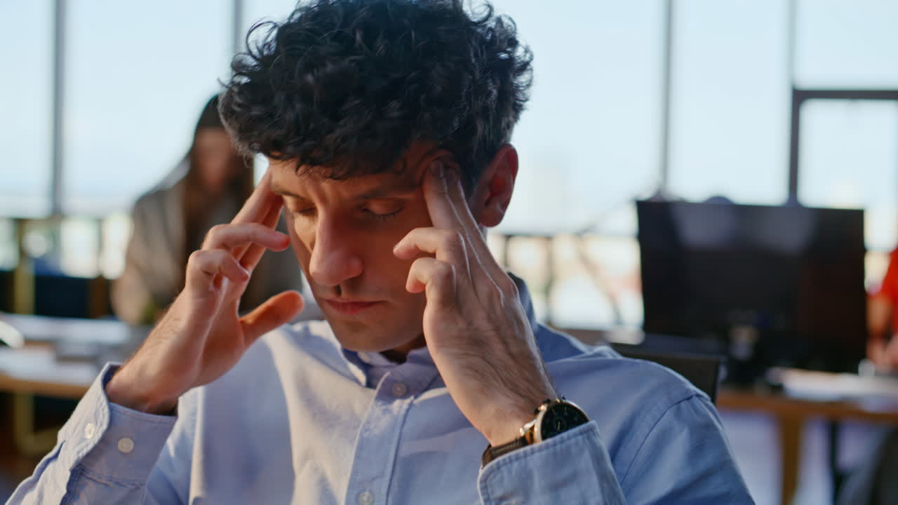 Uomo stanco che si massaggia le tempie mentre guarda il portatile cercando soluzioni a problemi di lavoro, primo piano