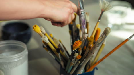 person's hand getting paintbrushes. - closeup shot