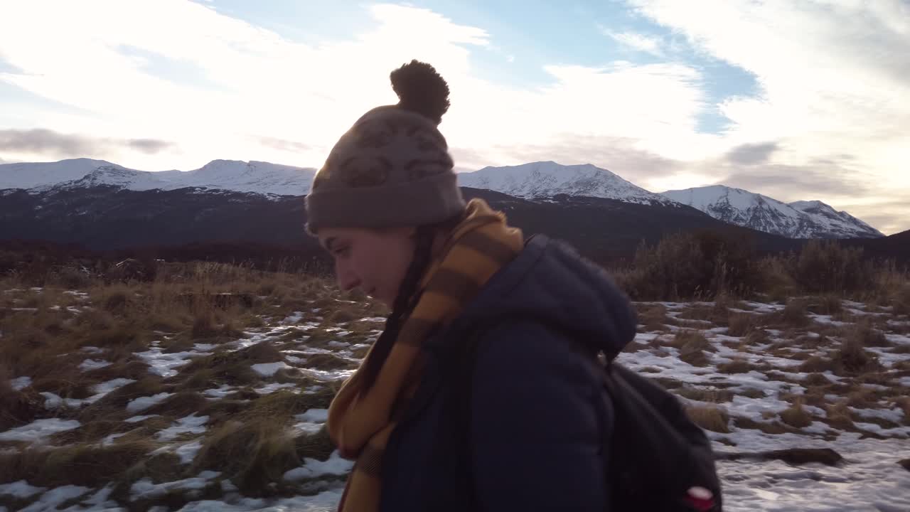 CAMION SINISTRA Donna vestita per l'inverno cammina su sentieri innevati con montagne sullo sfondo