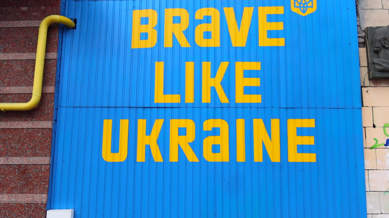 Big blue and yellow sign Be Brave Like Ukraine in Kyiv city center, 4K tilting down