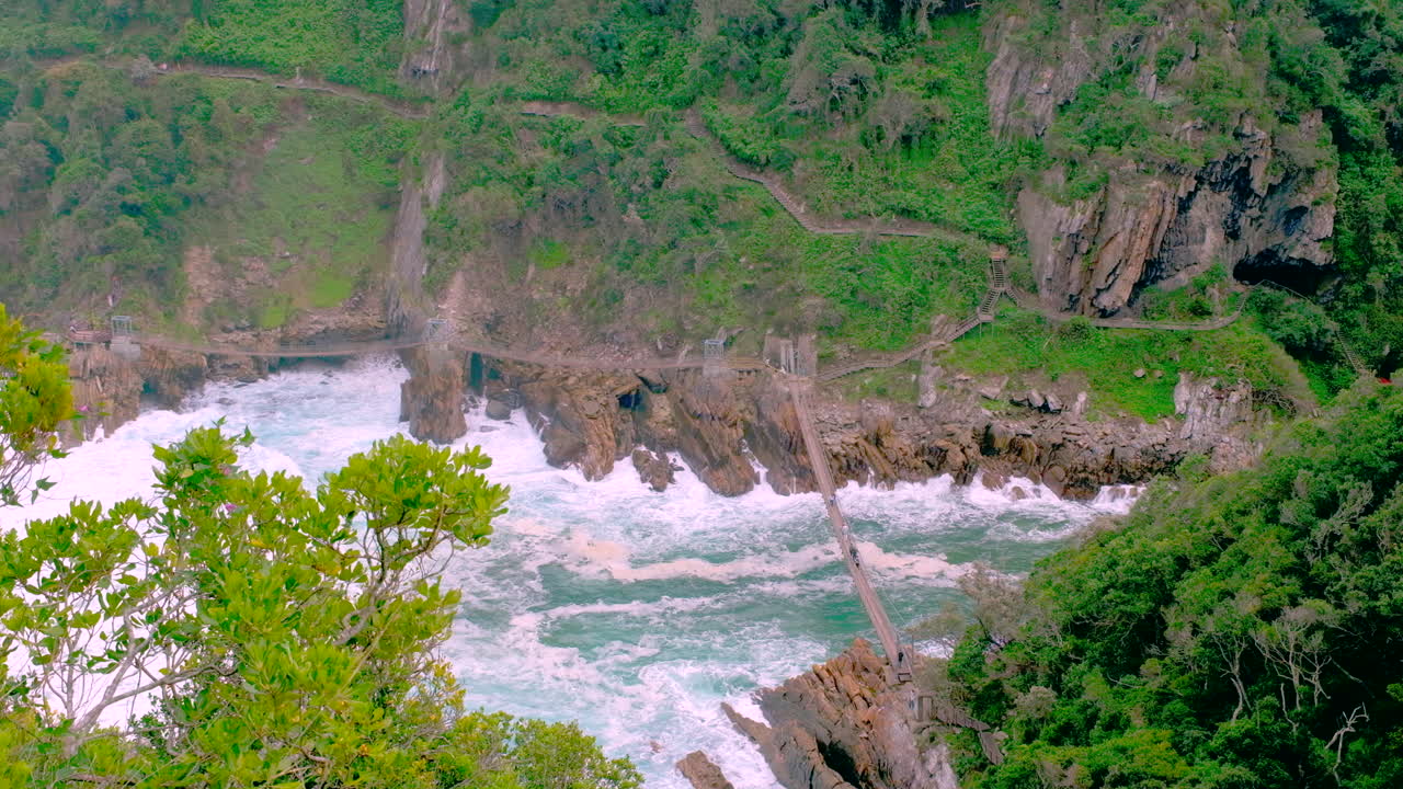 Elevated outlook view of foaming seawater under Storms River suspension bridge