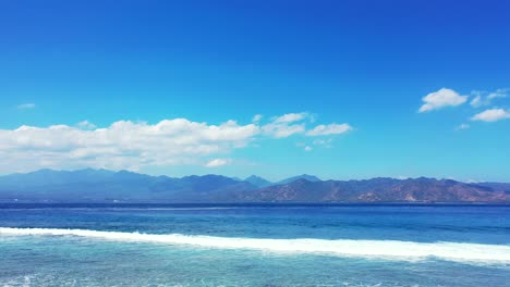 vivid colors of morning on seashore with white waves splashing over coral reefs under calm water of lagoon with a bright blue sky and white clouds background