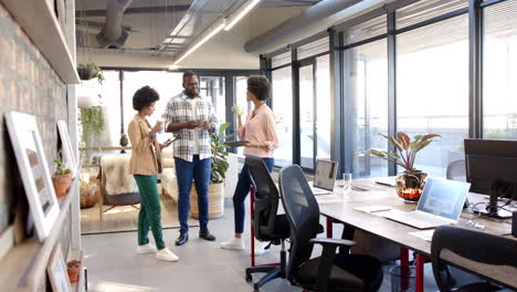 a diverse group of young professionals discussing work in modern office