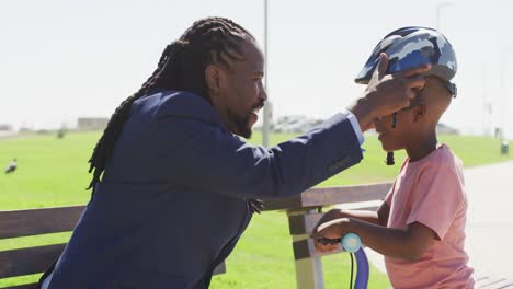 Video-of-happy-african-american-father-putting-helmet-on-sons-head