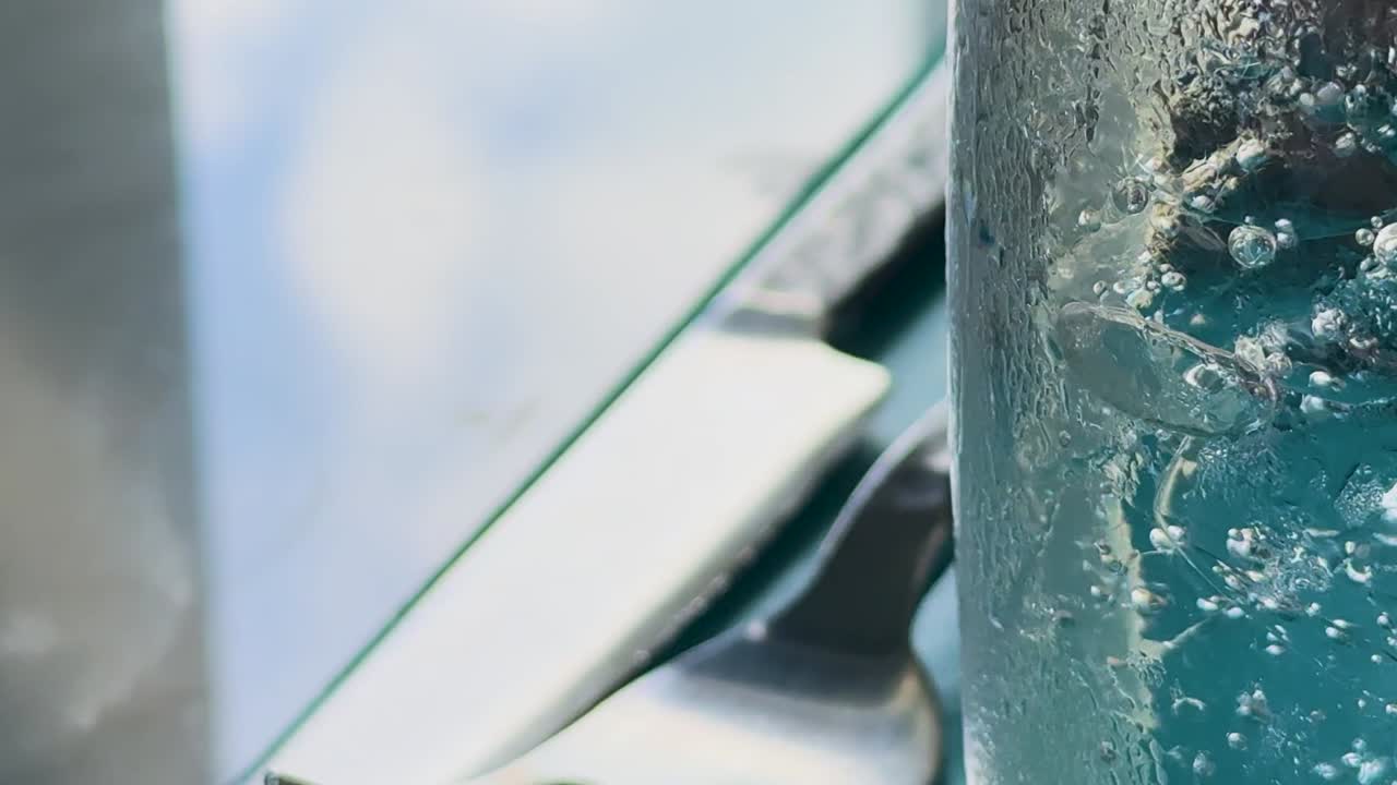 클럽 소다 거품이 유리잔에 상승하는 매크로 뷰, 자연 빛에서 식탁과 식구에 맞춰 설정