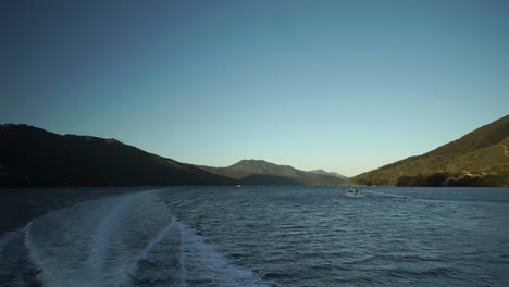 early morning sunrise boat cruise in marlborough sounds, new zealand with small boat and mountains in background