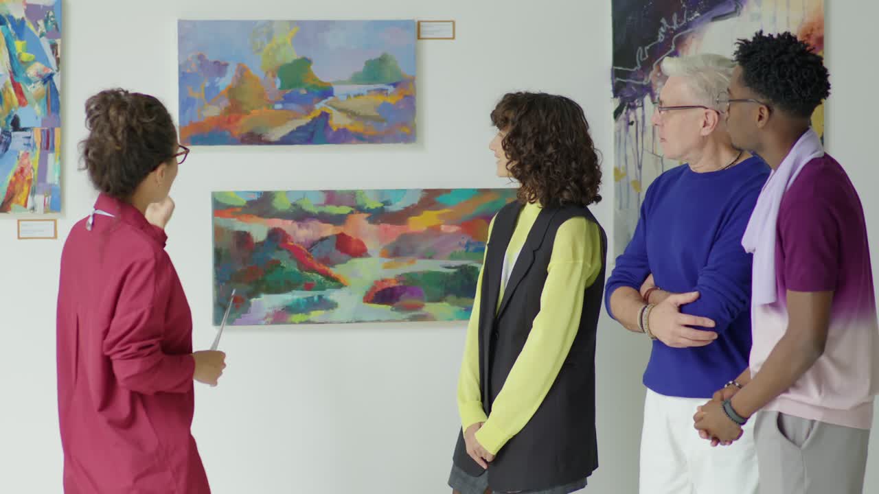 Gallery Guide Giving Tour to Visitors around Art Exhibition