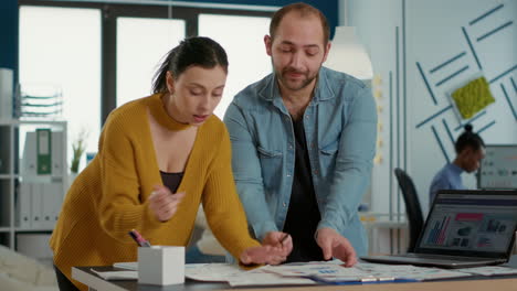 Colleagues-discussing-startup-business-strategy-comparing-sales-charts-with-analytics-on-laptop-screen