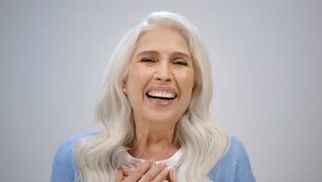 una anciana asombrada mirando a la cámara en el estudio. una anciana sonriente riendo adentro.