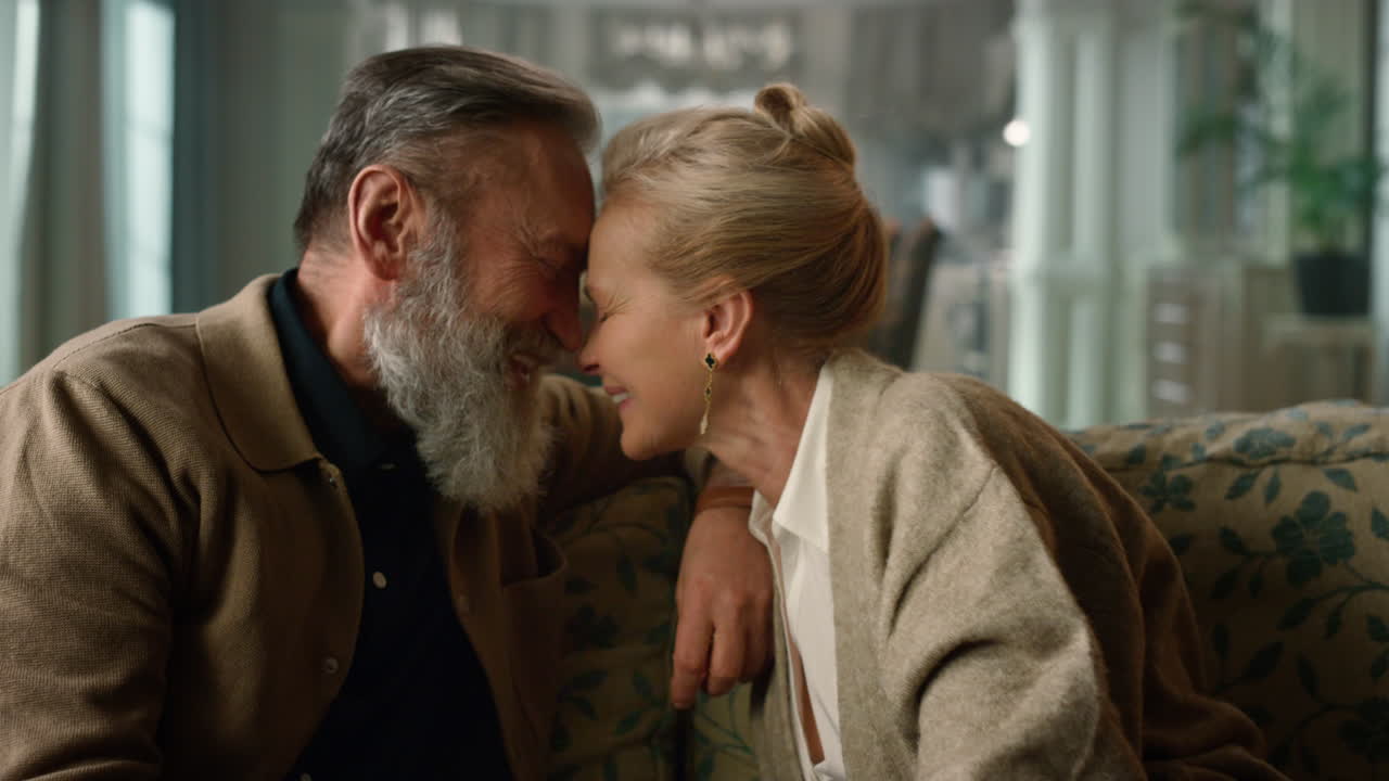 부드러운 성숙한 남자와 여자가 럭셔리 방에서 이마를 만지고 있습니다.