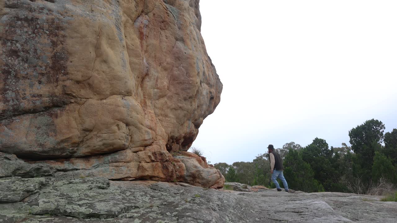 오스트레일리아 사막 의 바위 가 있는 바위 들 사이 에 서 있는 부시맨