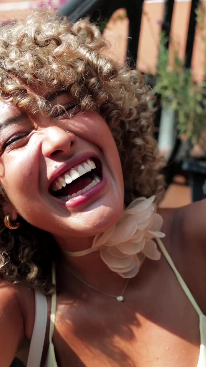 Giovane donna con capelli ricci che si scatta un selfie all'aperto