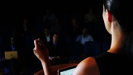 vista trasera de una mujer ejecutiva de negocios dando un discurso