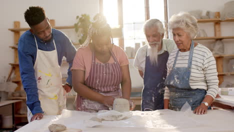 Happy-diverse-group-of-potters-cutting-clay-with-wire-in-pottery-studio