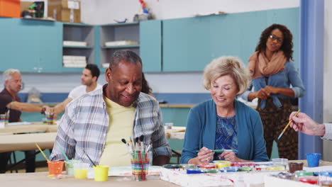 group of retired seniors attending art class in community centre with teacher