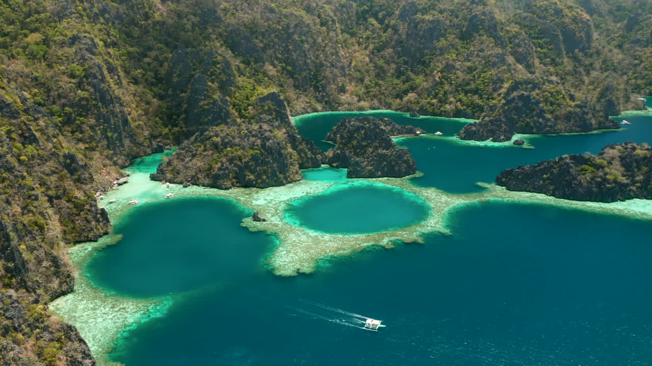 Ripresa aerea che mostra una barca a bilanciere vicino a un'isola tropicale deserta di El Nido, Palawan, Filippine.