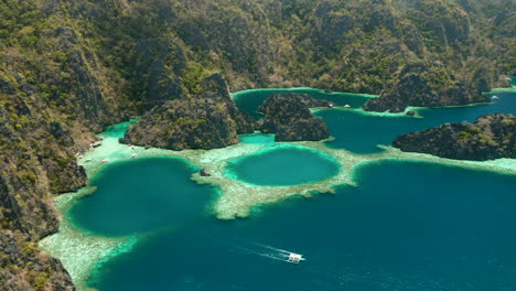 toma aérea que muestra un bote estabilizador cerca de una isla tropical desierta de el nido, palawan, filipinas