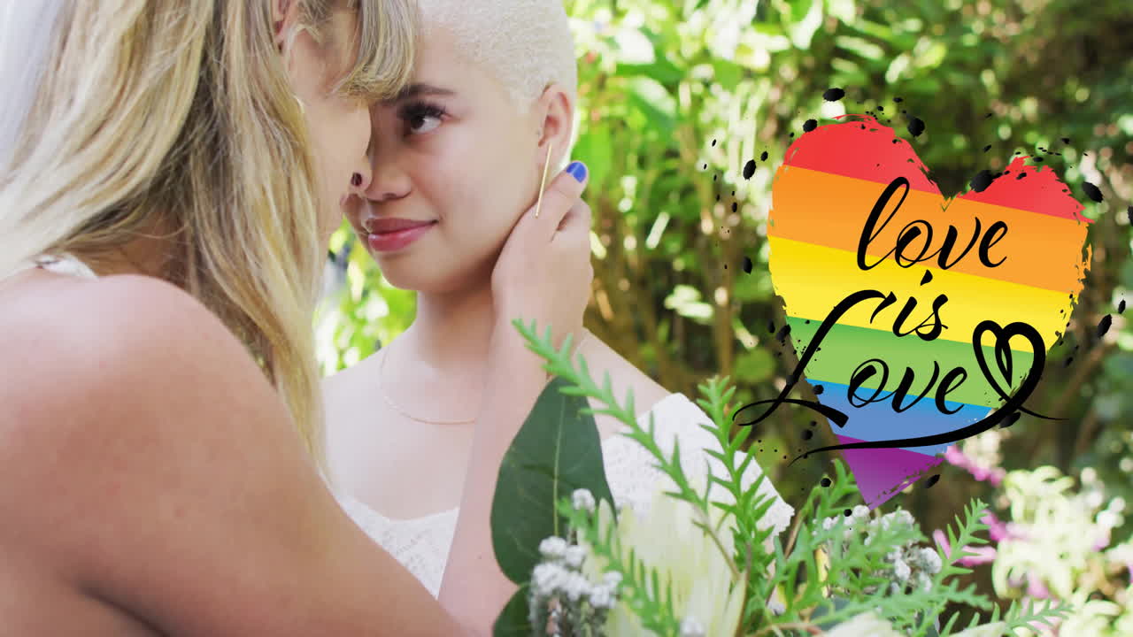 Animation of rainbow heart with love is love text over diverse female married couple embracing