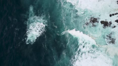 Drohne-Rotiert-über-Mächtige-Wellen,-Die-Auf-Felsige-Küste-Mit-Schaumigen-Oberflächen-Krachen