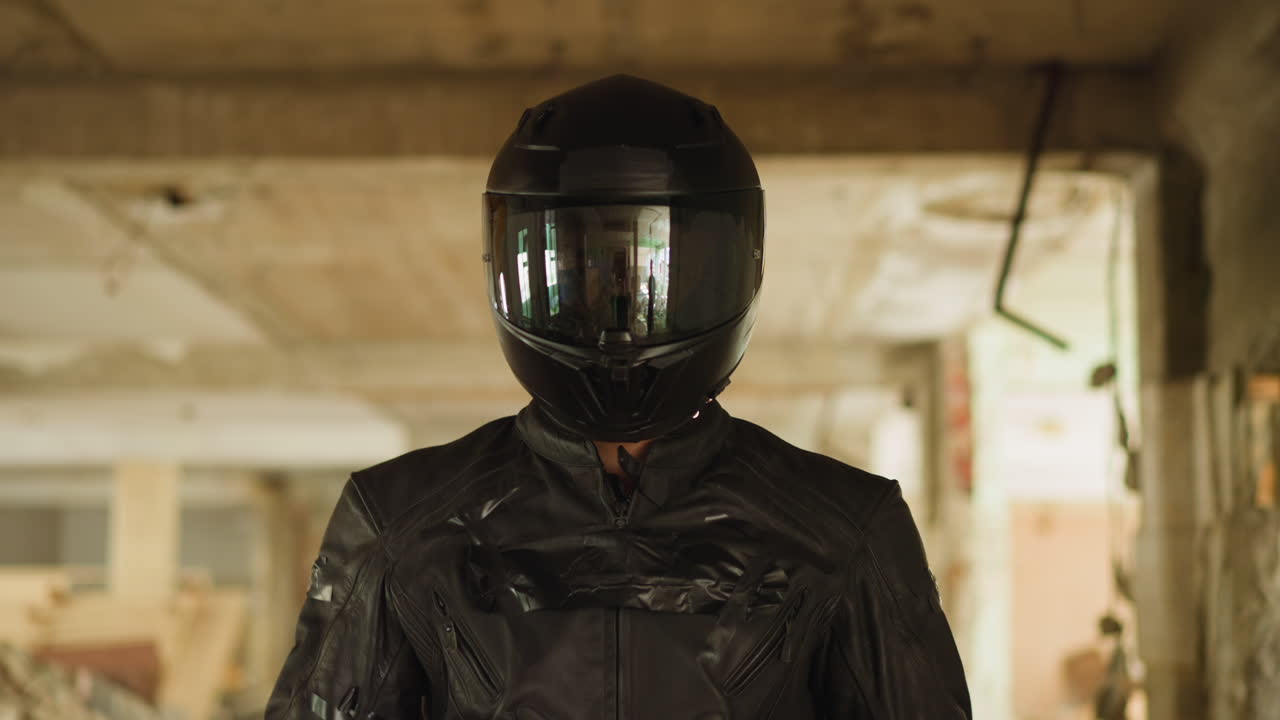 Man in jacket and black helmet walks along old building