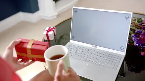 hands of biracial teenage girl with gift having laptop video call, copy space screen, slow motion