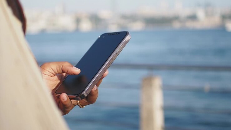 Person benutzt ein Smartphone am Wasser