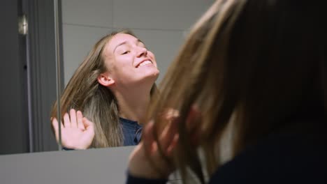 Young-lady-looks-amazed-in-mirror,-then-checks-her-face-proudly