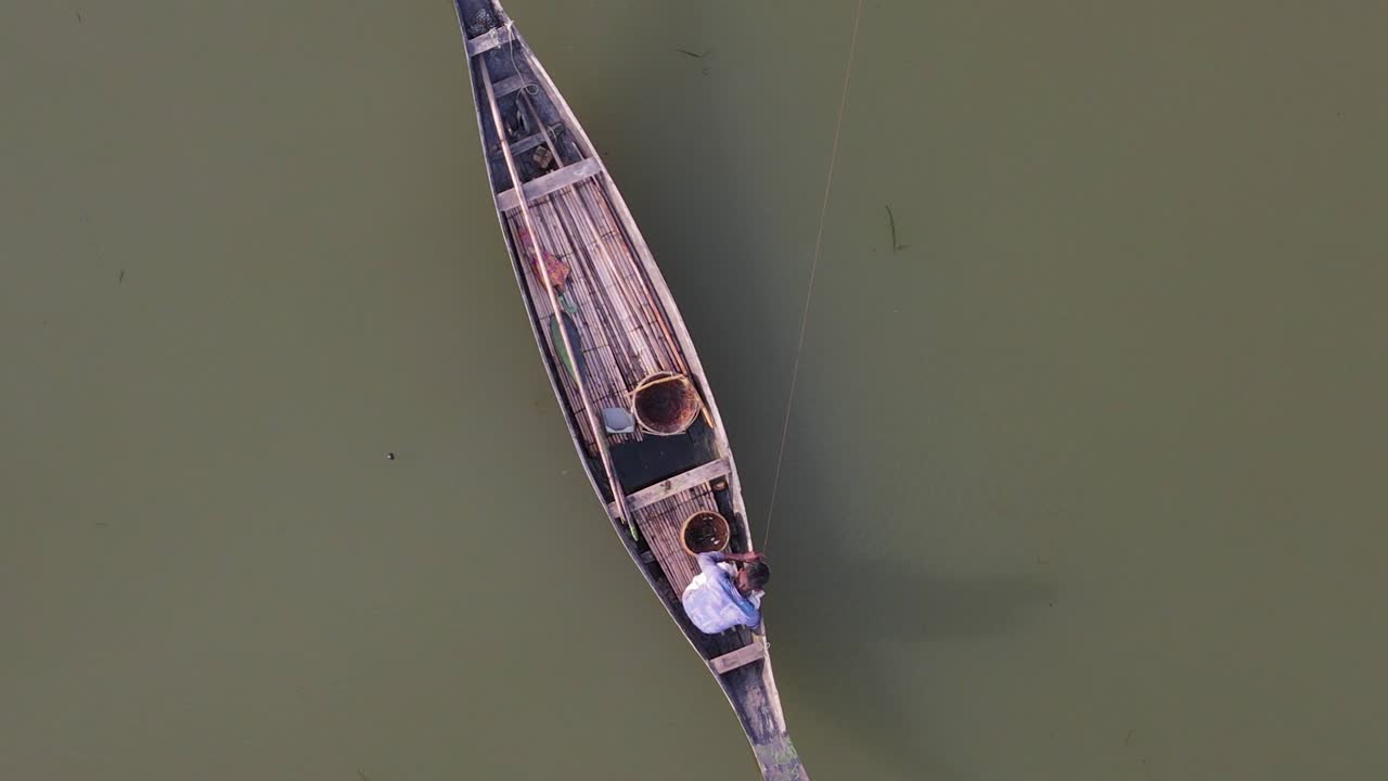 vista aérea de arriba hacia abajo de un pescador solitario en una línea tradicional de pesca de madera en el río ichamati