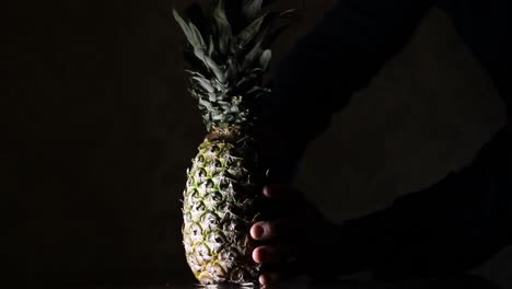 Macho-Cortando-Piña,-Ananas-Con-Un-Cuchillo-En-La-Oscuridad-1