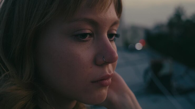 Pensive caucasian woman with nose piercing stands by herself, close-up profile