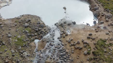 aerial flyover mud pool with rising steam in iceland during sunny day - expedition of iceland island in summer