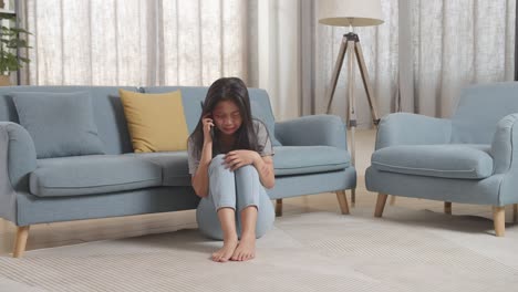 full body of young asian woman victim of violence with bruise on body crying and talking on smartphone asking for a help while sitting on the floor at home