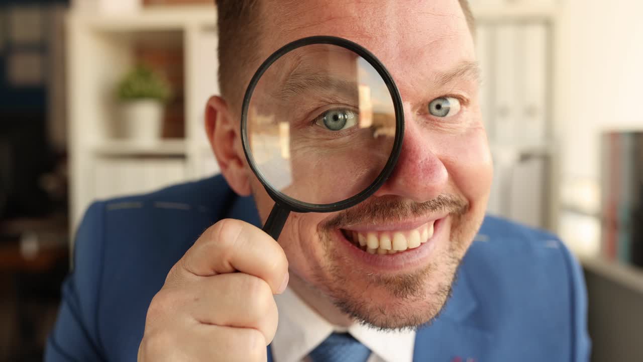 Young businessman smiling and holding magnifying glass to his face 4k movie