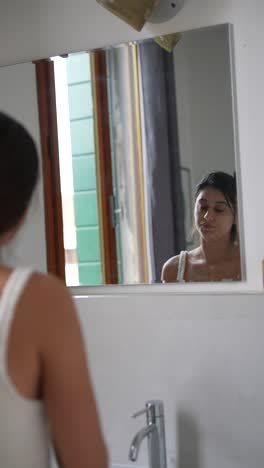 mujer mirándose a sí misma en un espejo del baño