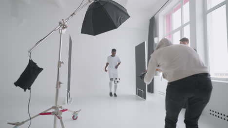 art director checking the photos on a monitor. professional crew team together in the studio. behind the scene of photo shooting professional football player and production set up in the big studio.