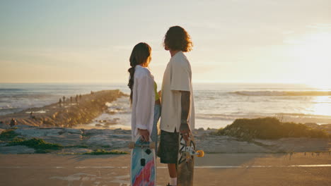 couple on a romantic sunset beach skateboarding