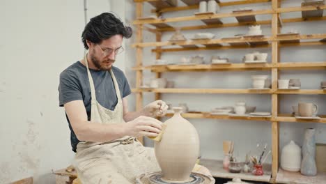 taller de cerámica. artista masculino esculpiendo un jarrón de cerámica hecho a mano en una rueda de cerámica en el estudio, en cámara lenta