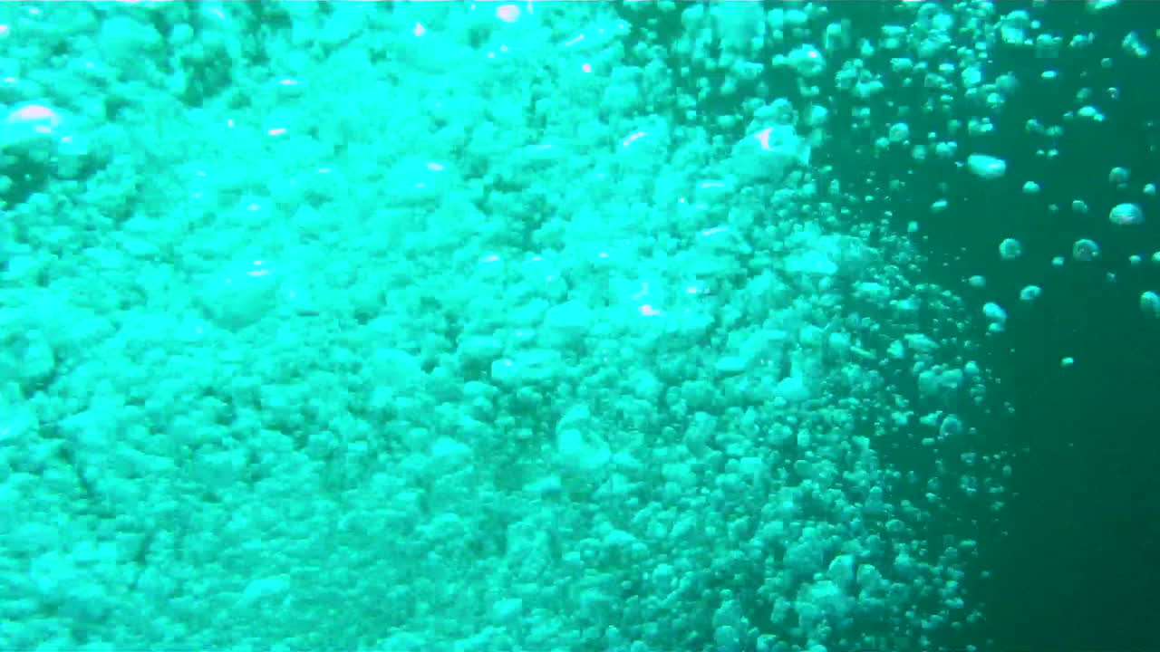 Underwater camera view passes through bubbles exhaled from scuba diver.