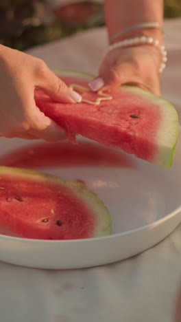 primer plano de la mano presionando el cortador en forma de estrella en una rebanada de sandía fresca en un plato blanco, destacando la carne roja vibrante y la corteza verde para un toque creativo, sandía