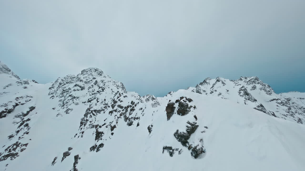 Snow-covered mountains in Tromsø under a cloudy winter sky, peaceful and cold