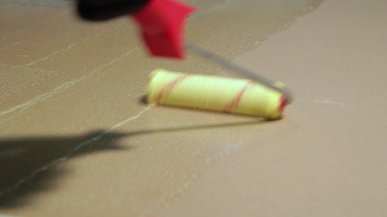 рабочий окрашивает пол в ванной комнате гидроизоляцией перед укладкой плитки