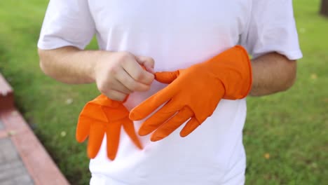 el hombre se pone y se quita los guantes protectores naranjas en las manos preparándose para empezar a limpiar