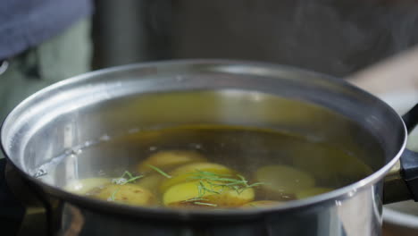 adding rosemary to pot while cooking potato