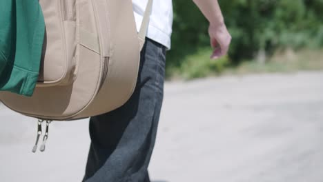 young man walking with guitar on street near forest