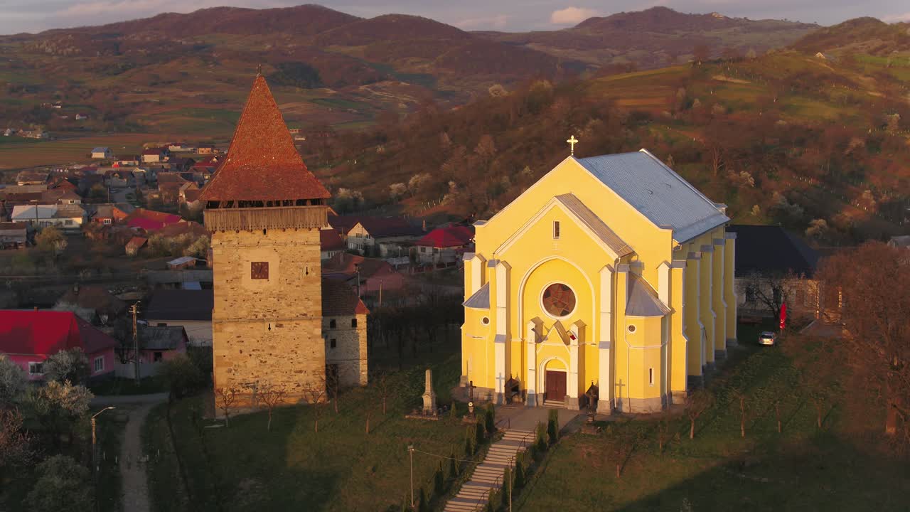 Aerial Shot of Yellow Church and Medieval Tower in Dumitra Traditional Mountain Village at Sunset