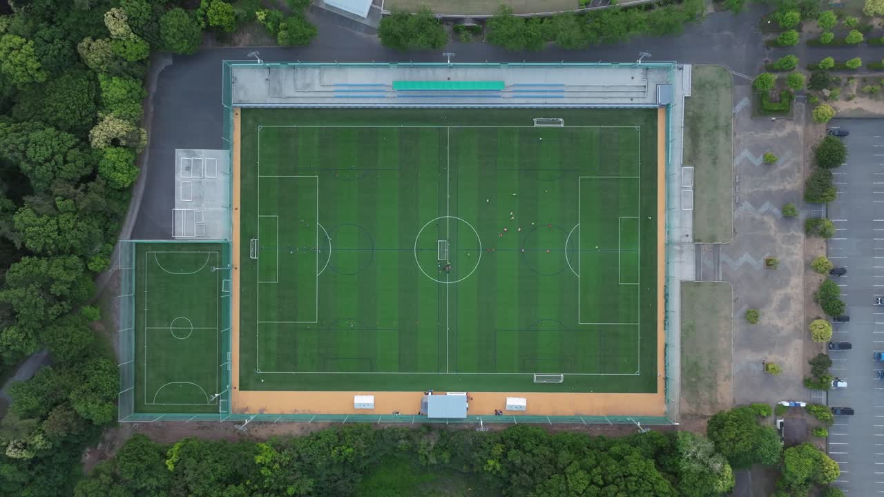 drone aéreo zoom en el campo de fútbol del campus desde la vista superior se acerca al campo verde