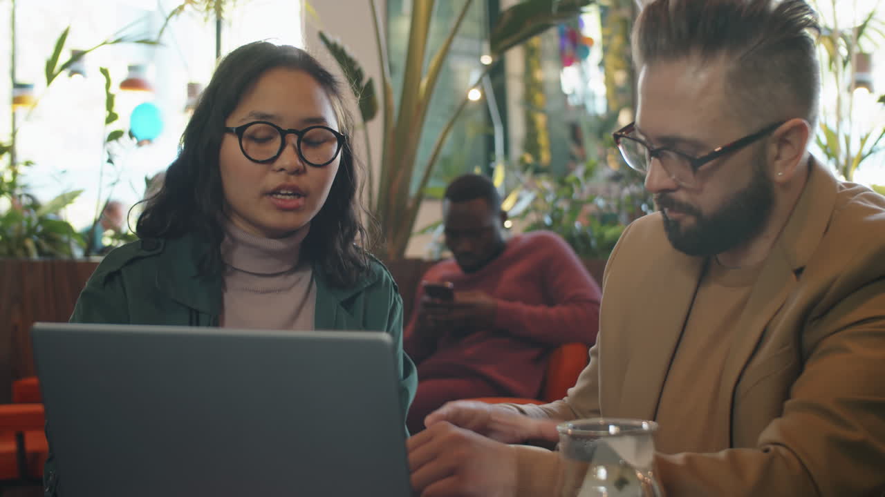 Multiethnic Business Partners Drinking Tea and Using Laptop in Cafe