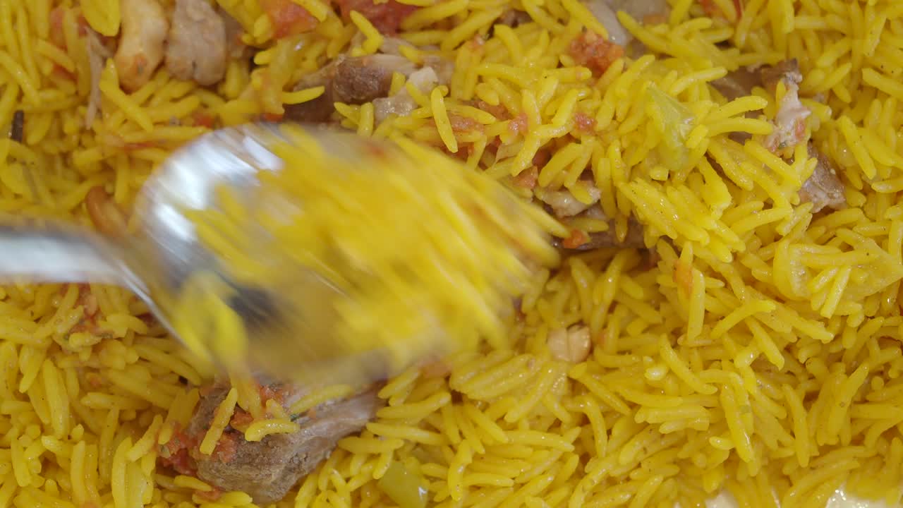 un primer plano de un plato de arroz amarillo con carne